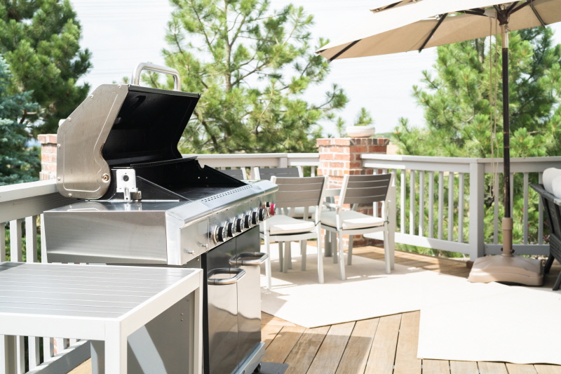 Outdoor six-burner gas grill on the back patio of a luxury single-family home.